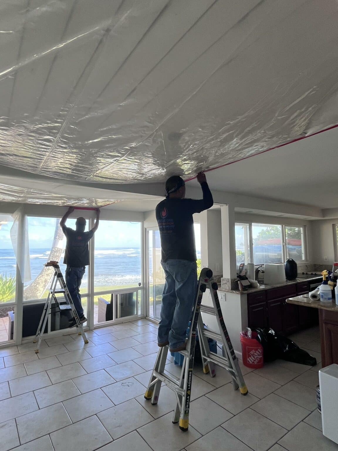 Rescue One technician hanging containment sheeting in an oceanfront condo
