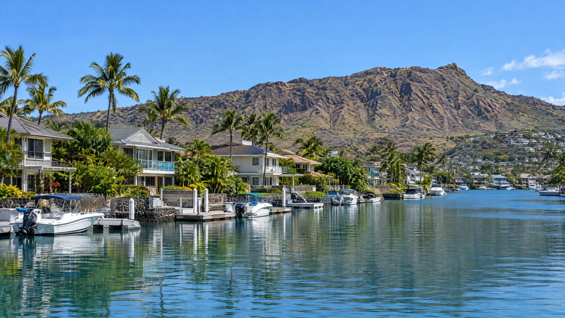 Waterfront homes and docked boats along a calm marina channel in Hawaii Kai.