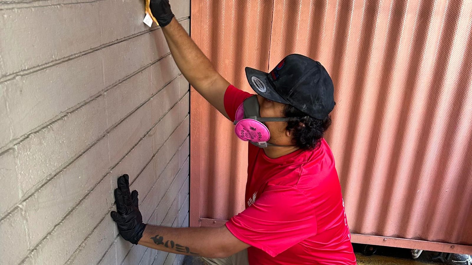 A Rescue One technician in a respirator treating a wall after water damage.